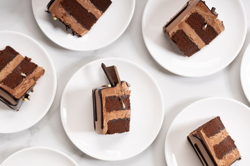 Pieces of layered dark chocolate cake on white plate