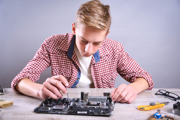 Man repairing broken computer, video card,memory RAM, cooler, processor,hard drive. Young repairer...