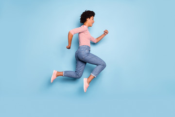 Fototapeta na wymiar Full length body size side profile photo of cheerful positive nice pretty running jumping girl for sales in jeans denim striped shirt isolated blue pastel color background