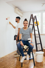 young couple decorating and painting indoor walls in their home