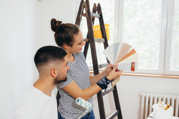 young couple choosing the right color for wall in their home