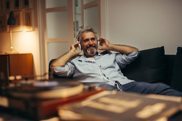 mid aged man relaxing in his home listening to a music