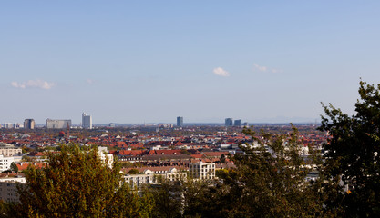 Munich skyline photographed from the Olympia hill in Munich Olympiapark on a clear day with the Alps on the background