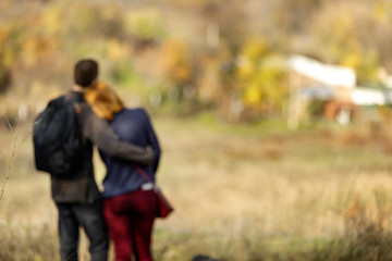 Fototapeta premium blur couple in love standing on a hill enjoying the beautiful view in autumn. Man hugging woman. Back view