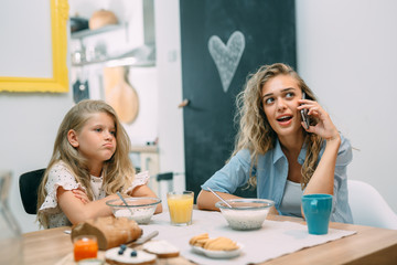 mother ignoring her daughter while using mobile phone