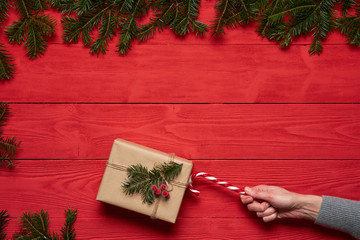 Woman's hand pulling a Christmas present with traditional Christmas candy stick