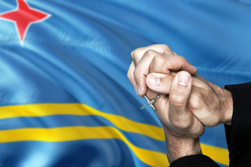 Aruba flag and praying patriot man with crossed hands. Holding cross, hoping and wishing.