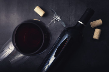 red wine bottle and glass on black marble stone background. top view