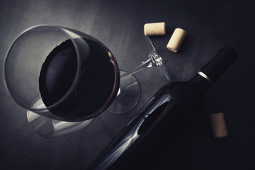 red wine bottle and glass on black marble stone background. top view