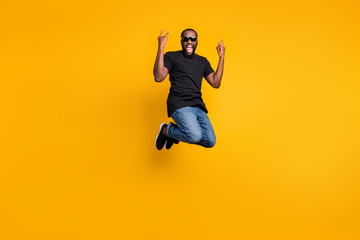 Obraz premium Full length photo of crazy funky afro american guy jump fun rock concert scream show horns wear youth style denim jeans isolated over yellow color backround