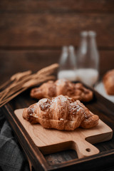 Almond croissant with custard filling on wood background.