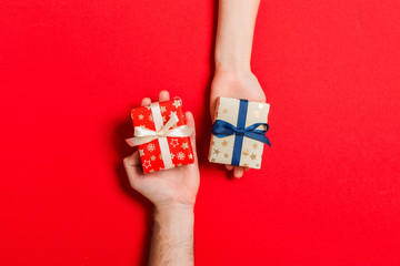 Top view of a woman and a man exchanging gifts on colorful background. Couple give presents to each...