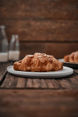 Almond croissant with custard filling on wood background.