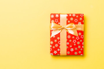 Top view Christmas present box with gold bow on yellow background with copy space