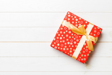 Beautiful gift box with a colored bow on the white wooden table. Top view banner with copy space...