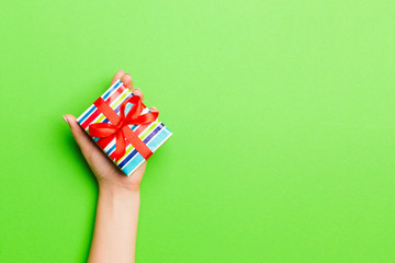 Fototapeta premium Top view of female hands holding christmas or other holiday handmade present box package in the palms, flat lay table background with copy space