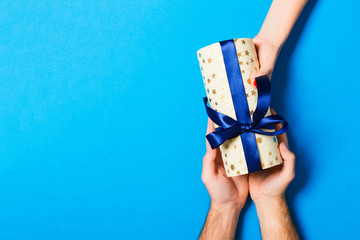Top view of couple giving and receiving a gift on colorful background. Romantic concept with copy...