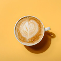 Top view Creative layout made of americano cappuccino latte art coffee in hard light on colorful yellow background. Hard shadow, minimal flat lay style. Food concept.