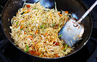  Indian street food vendor making vegetarian noodles,frying in pan   