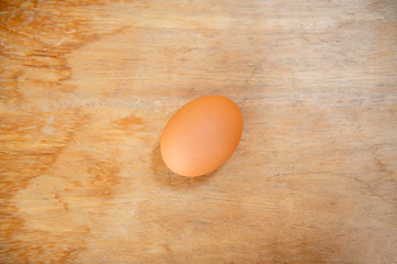 Raw single brown chicken egg isolated on a wood table, cooking healthy food