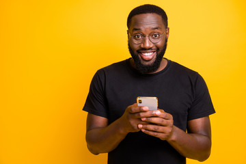 Photo of trendy cheerful positive handsome man smiling toothily in spectacles browsing through his...