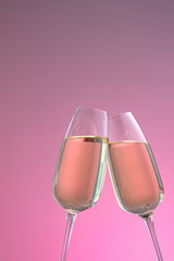 two glasses of sparkling wine on a pink background