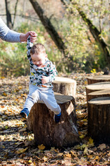 Two-year-old boy have fun jumping on their stumps.Parents help his.