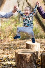 Two-year-old boy have fun jumping on their stumps.Parents help his.