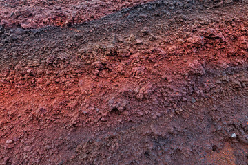 A cut of soil with rocks and red soil
