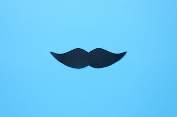 Black paper moustache centered on a blue background. Men's health and prostate cancer awareness...