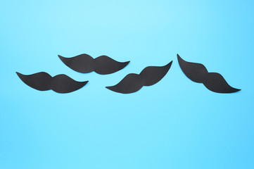 Several black paper moustache on a blue background. The concept of awareness of men's health and prostate cancer.