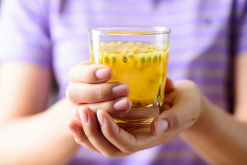 Woman hand holding glass of passion fruit juice, healthy drink