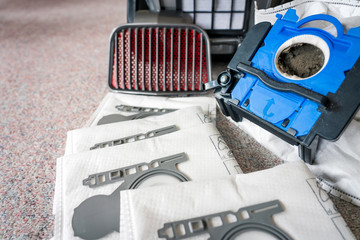 Vacum cleaner sitting on the floor with new and old dust bags and hepa filter in the back. Spare...