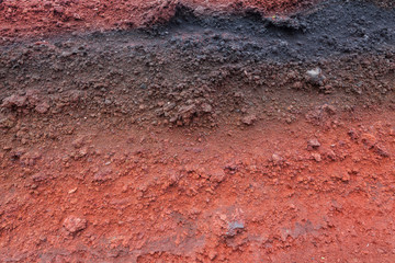 A cut of soil with rocks and red soil