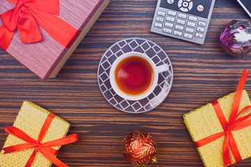 Cup of tea, gifts, laptop and IP phone on the wooden background. Christmas and new year concept. Top view. Space for a text.