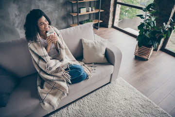 High angle view photo of beautiful dark skin lady hold hot coffee beverage cup enjoy weekend home sit cozy couch casual outfit covered with blanket living room indoors