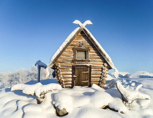 The wooden hut of a fairy-tale witch, covered with snow, on a frosty winter day.