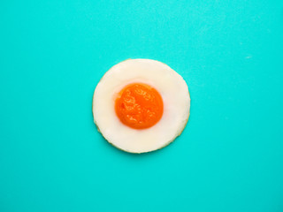 Close-up and top view perfect circle fried egg on blue-green color background with copy space.