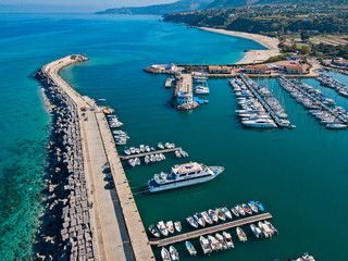 Aerial view of boats moored at the Port of Tropea, Calabria, Italy. Houses overlooking the sea. Beach and Sanctuary on the horizon. Italian coasts