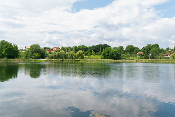 Fototapeta na wymiar calm lake with green vegetation and houses in the background