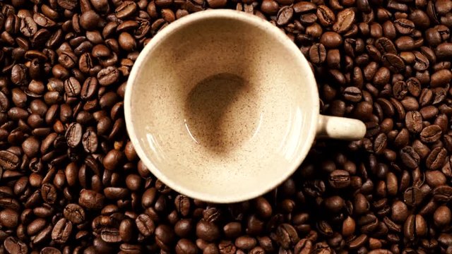 Coffee time. Small cup on roasted coffee beans background. Top view