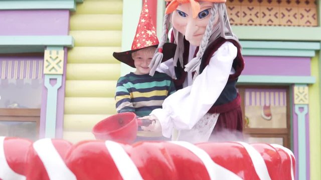 A boy at the Halloween festival in Sochi Park is cooking a magic potion with a woman’s yaga