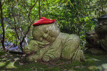 Bull - symbol of japanese horoscope. Childish Jizo stone statue wearing knitted and cloth hats with zodiac animal.