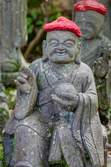 Old stone statues of Buddhist monks and nuns wearing knitted and cloth hats