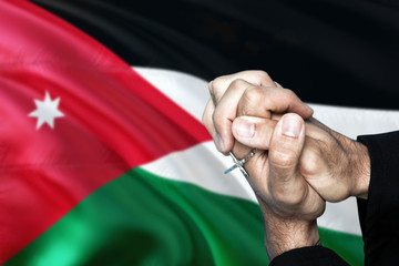 Jordan flag and praying patriot man with crossed hands. Holding cross, hoping and wishing.