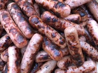 Background texture: a pile of grilled sausages. Grilled chicken sausages for a picnic. Pork and veal in the form of sausages.