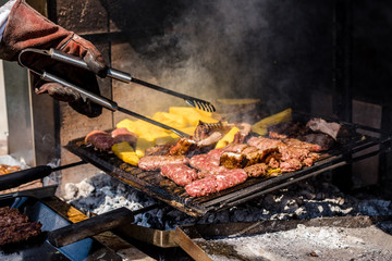 Beef meat with polenta and sausages cook on the barbecue flame, viewed from above