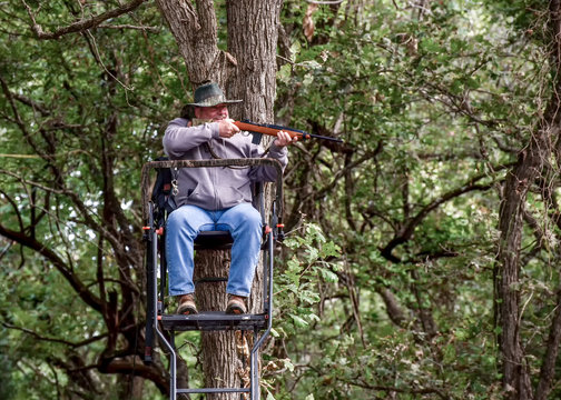 Hunter in tree stand taking aim at his game in hopes of a successful hunt