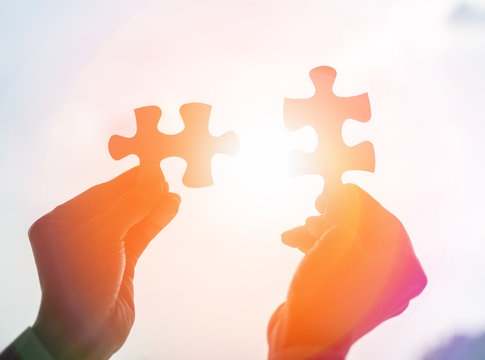Autism and autistic ,child connect puzzle together. Hands of business holding pieces of jigsaw as a symbol for solution building teamwork, partnership, cooperation, in workplace.