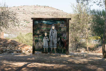 A stand with a picture of ancient settlers with holes for faces for photographing at the entrance to the archaeological site of Tel Shilo in Samaria region in Benjamin district, Israel - obrazy, fototapety, plakaty
